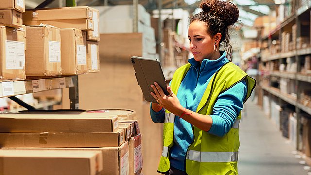 Mitarbeiterin im Großhandel nutzt wegeoptimierte Funktionen zur Einlagerung von Waren im Lager