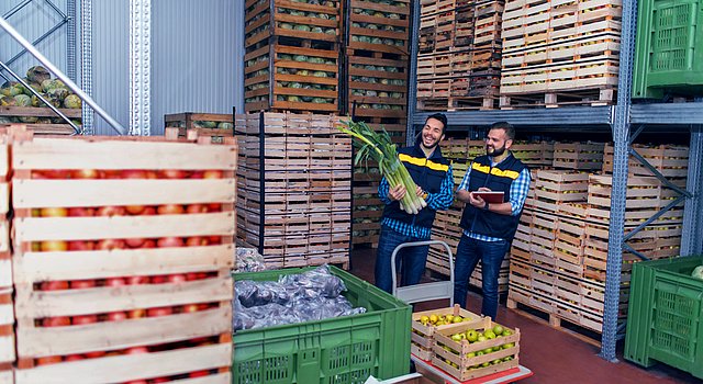 Fruchtgroßhändler im Lager mit ein paar Stangen Lauch in der Hand