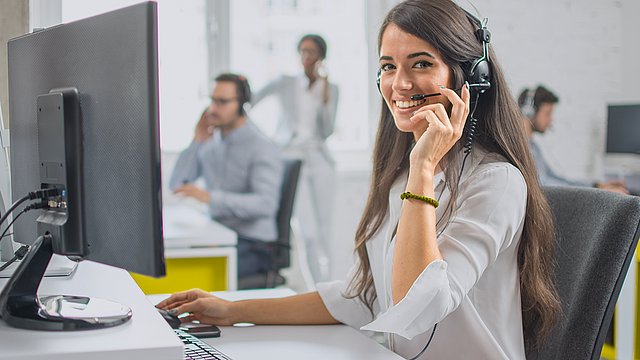 Mitarbeiterin kommuniziert mit Kunden telefonisch und nutzt Software