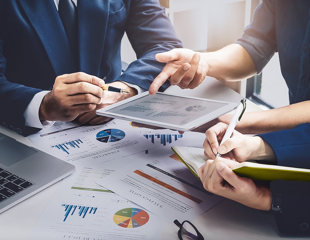 Mitarbeitende der Finanzbuchhaltung mit Ausdrucken und Tablet zu ihren Finanzen